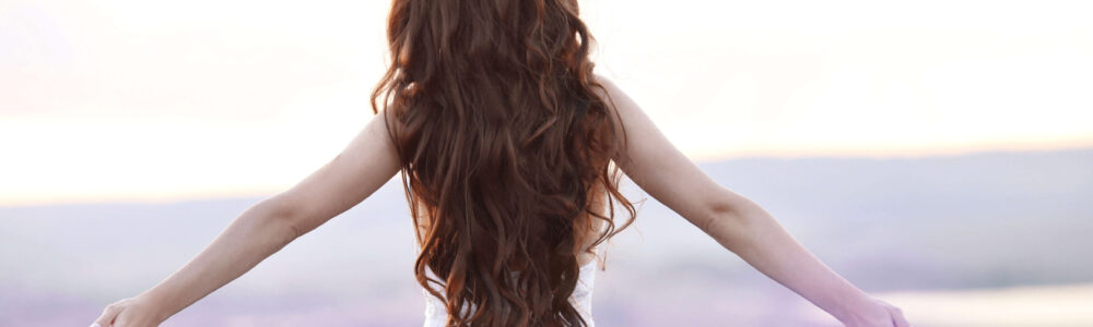 Frau mit wunderschönen langen braunen Haaren läuft durch ein Lavendelfeld