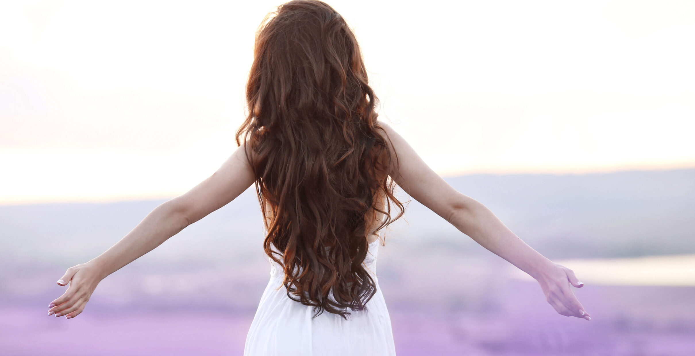 Frau mit wunderschönen langen braunen Haaren läuft durch ein Lavendelfeld